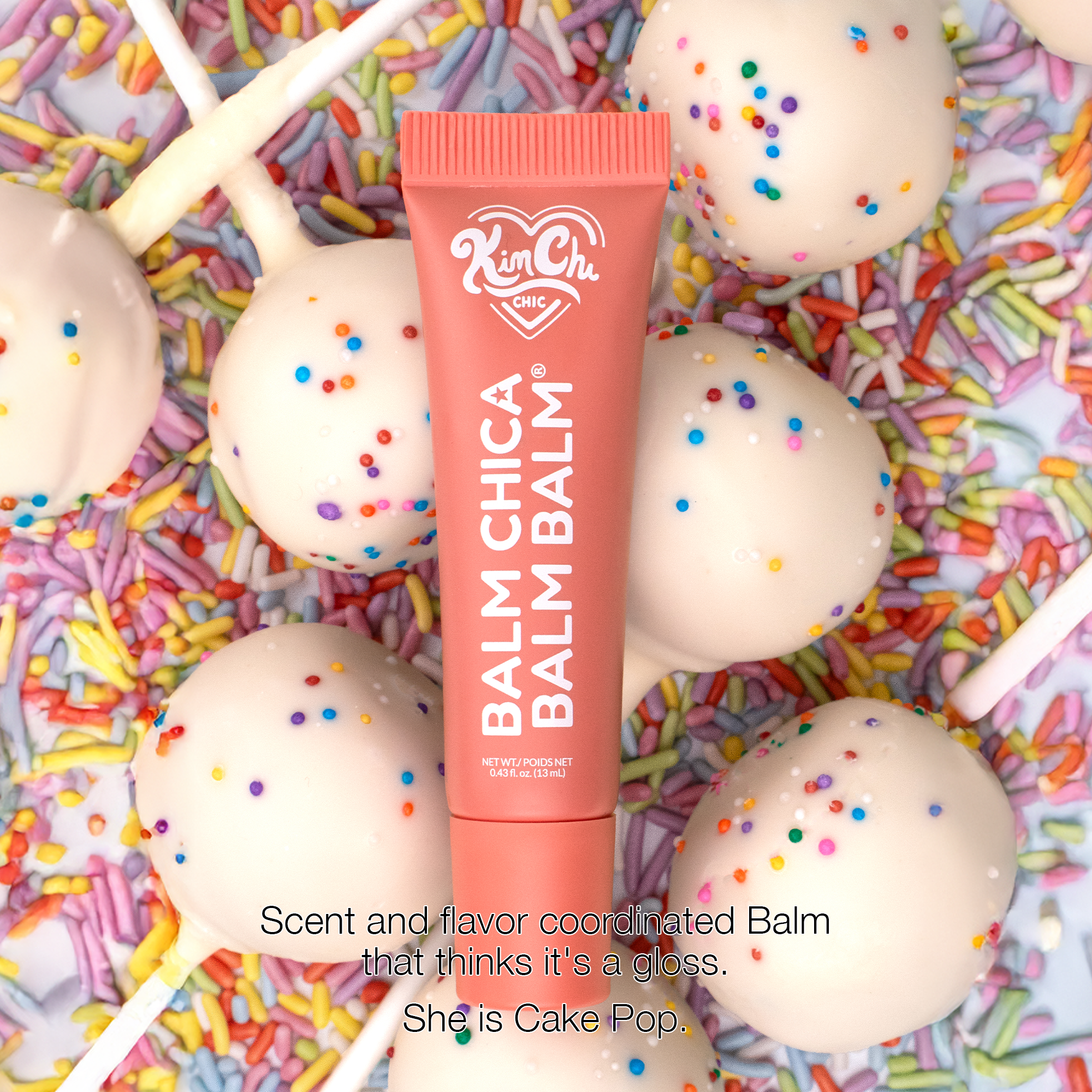 KimChi Chic Balm Chica Balm in pink tube, flavored balm with cake pop scent, surrounded by cake pops and sprinkles.