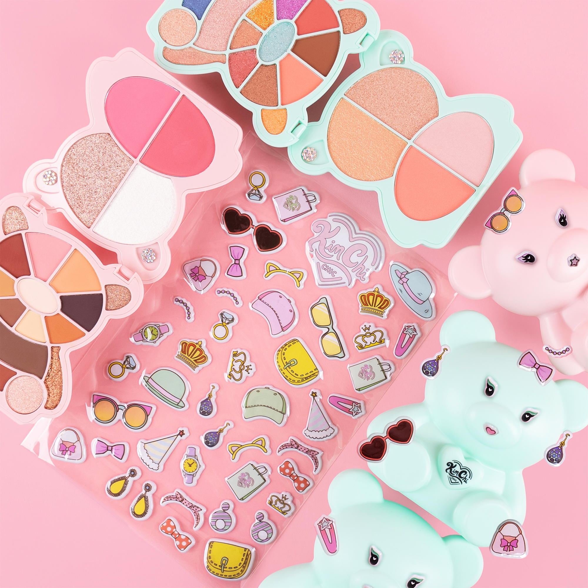 Colorful bear-shaped makeup palettes with blush and eyeshadow, plus fun stickers on a pink background.