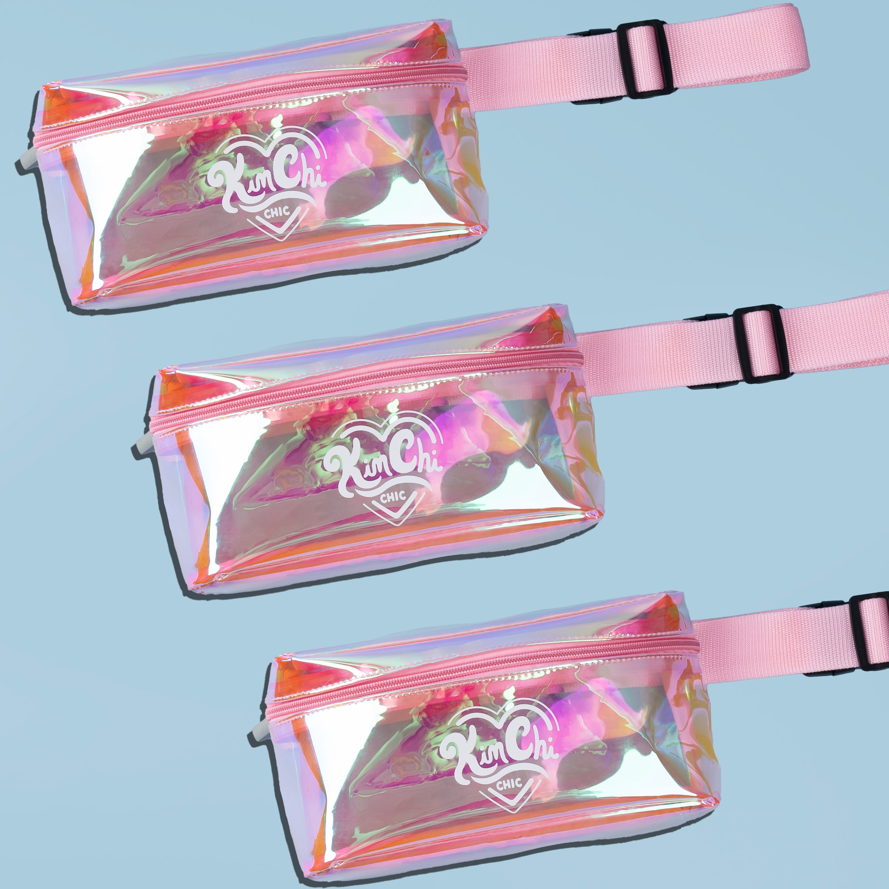 Three holographic fanny packs with pink straps on a blue background