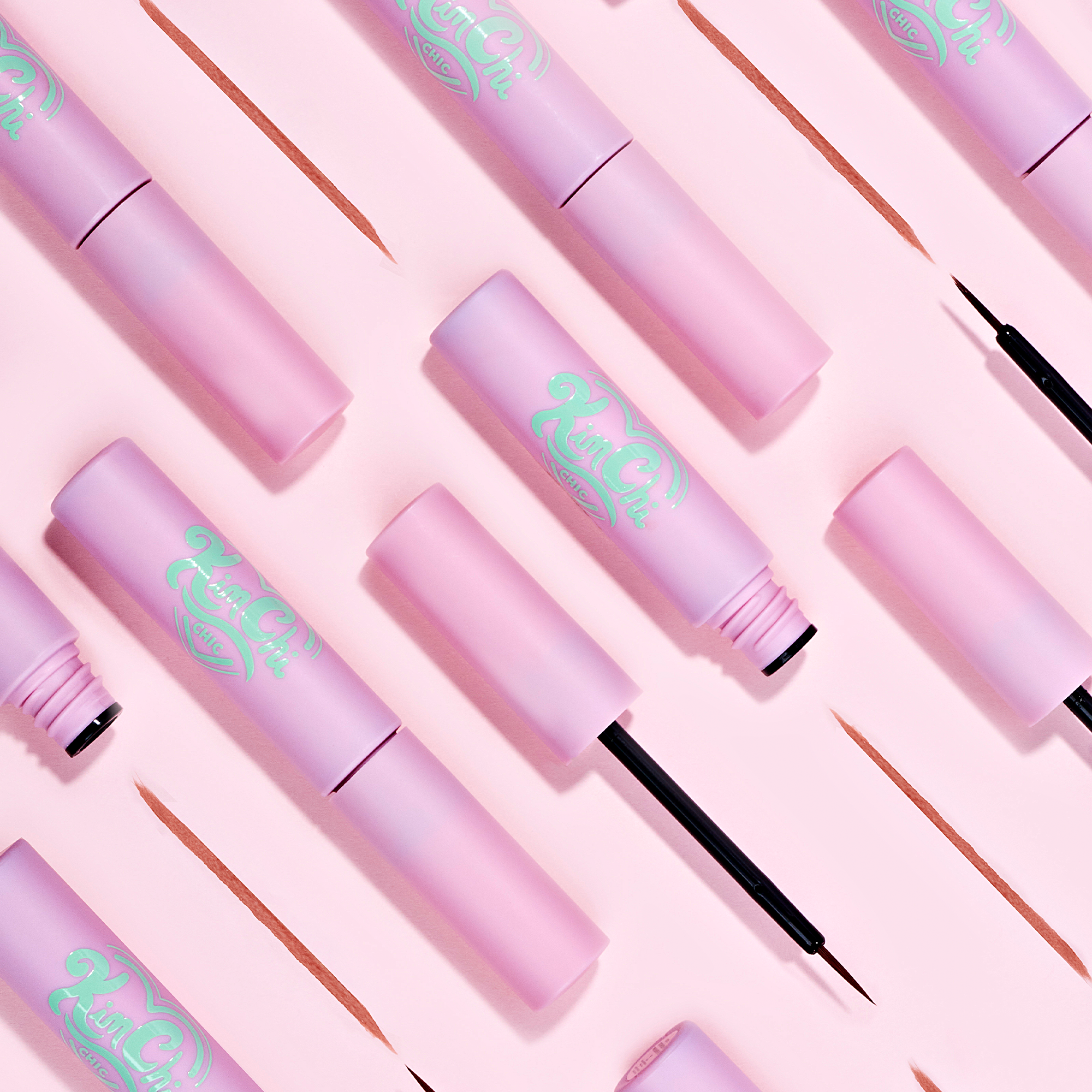 Kim Chi pink liquid eyeliner with precision brush, glossy finish on a soft pink background.