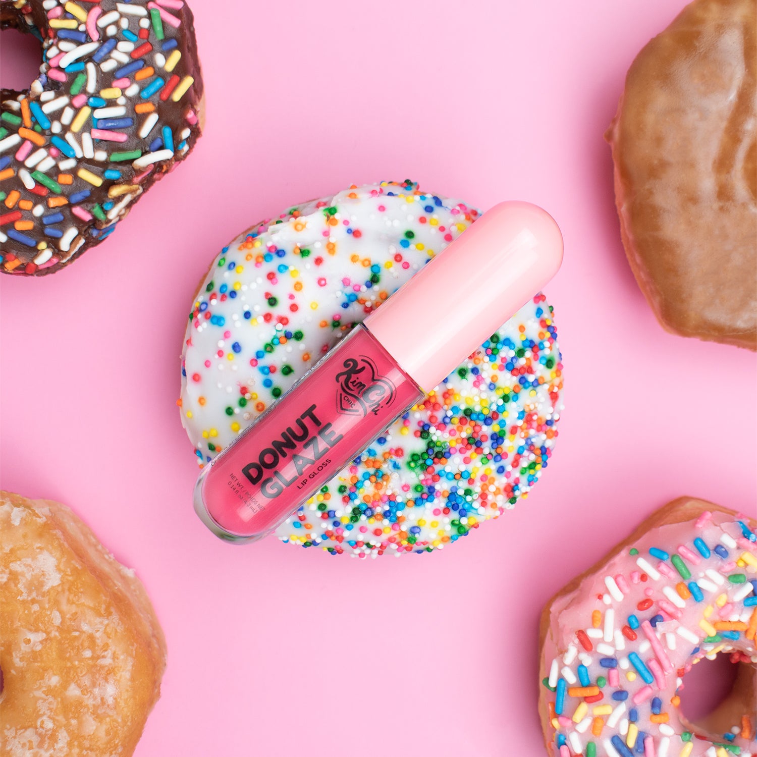 Colorful donuts with a lip gloss tube placed on a donut covered in sprinkles.
