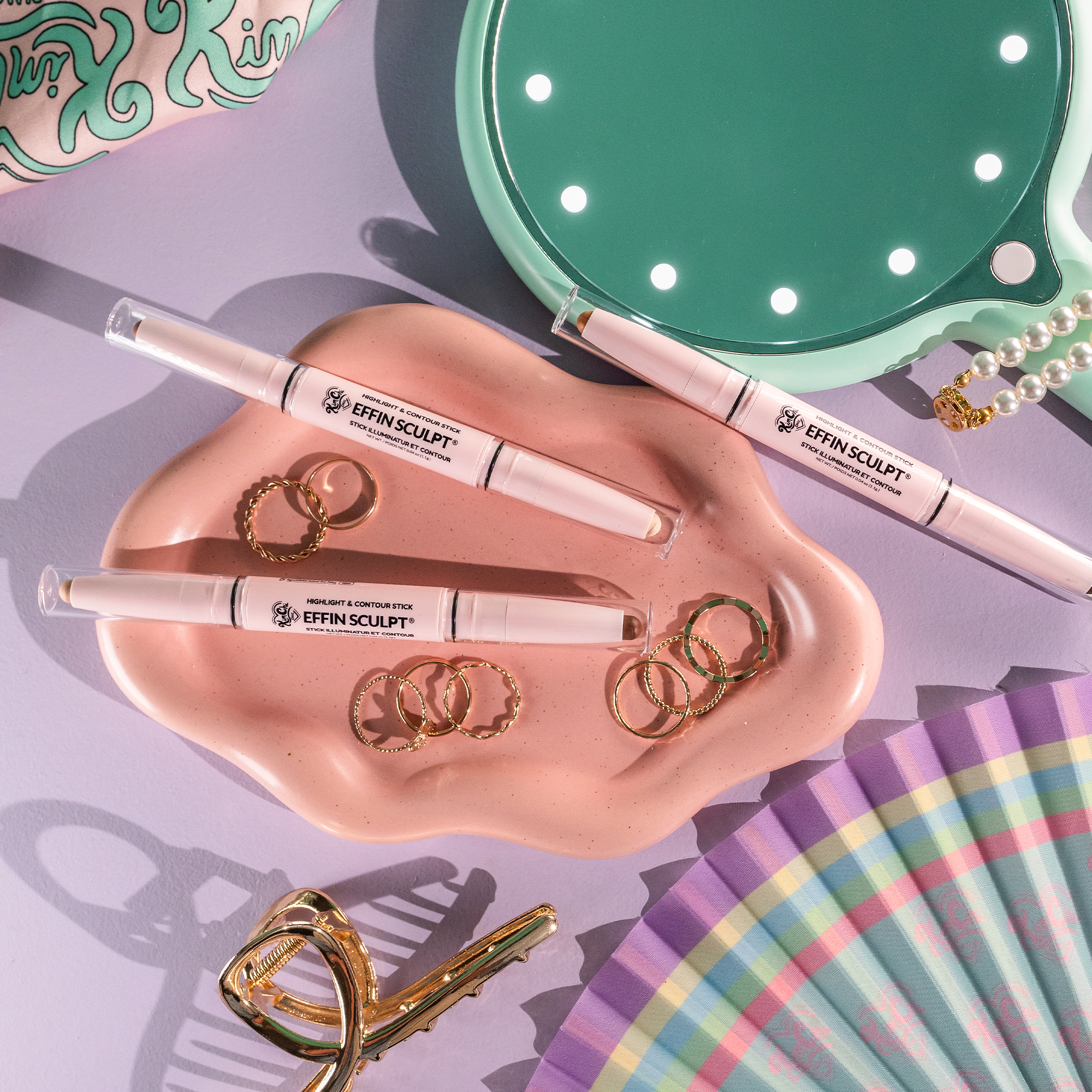 Cosmetic products arranged on a colorful surface with rings and accessories