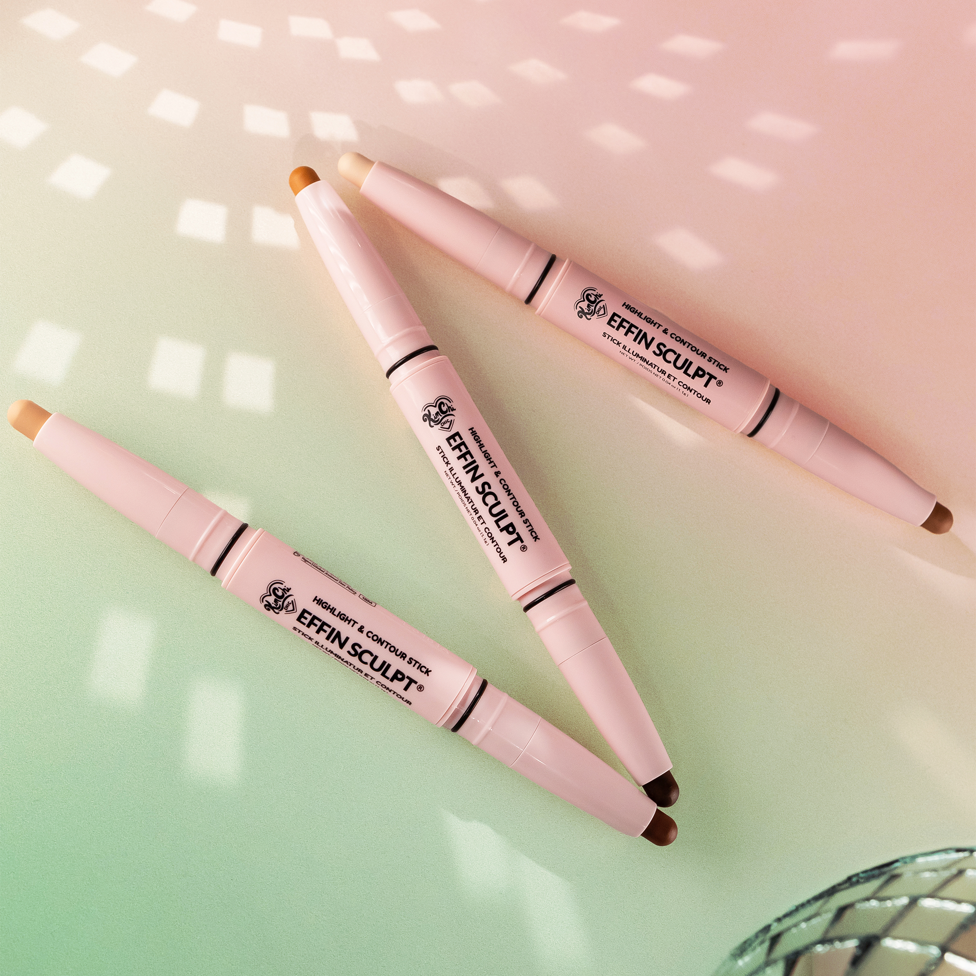 Three sculpting makeup sticks arranged on a gradient background.
