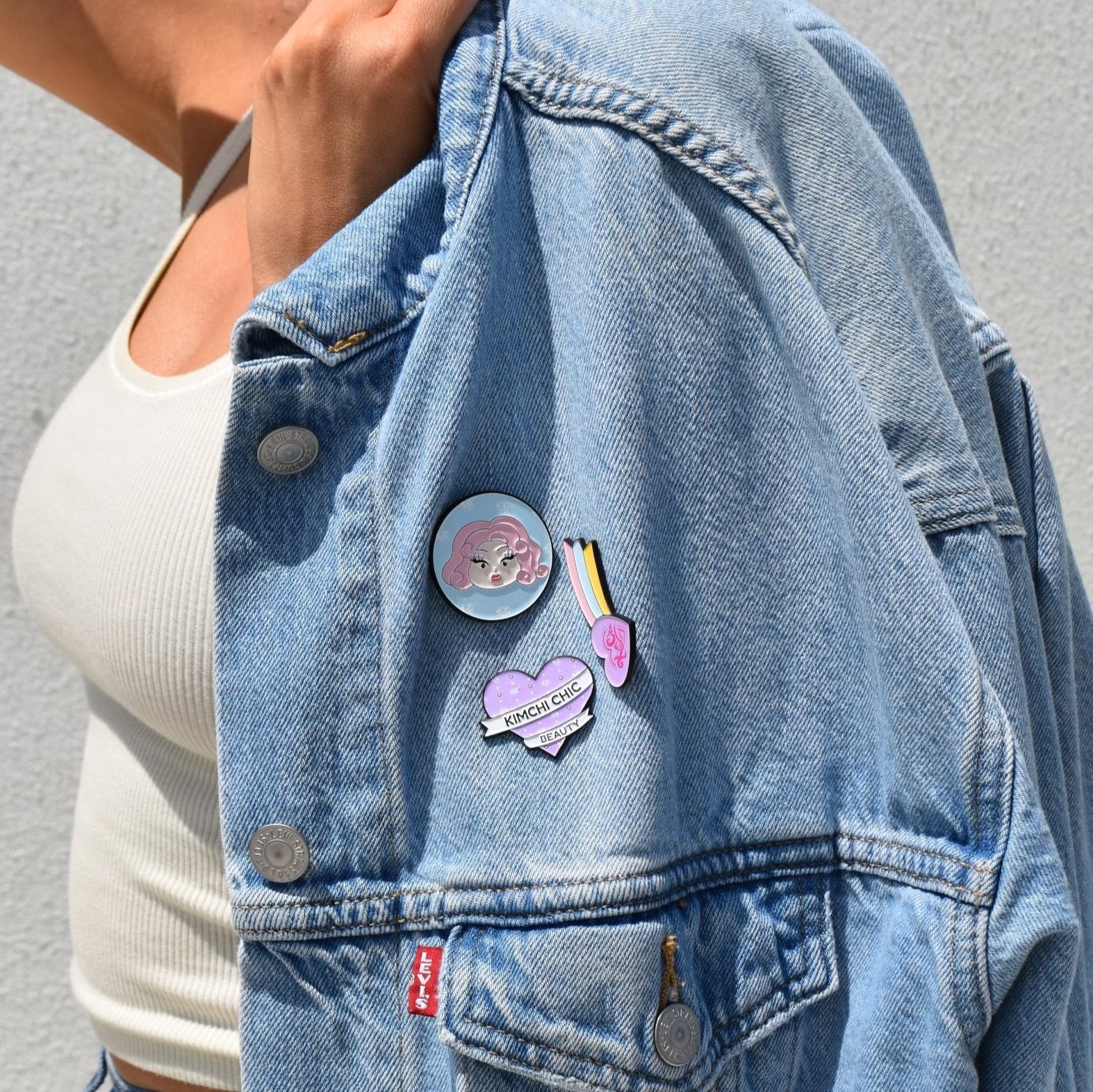 Person wearing a denim jacket with various colorful pins