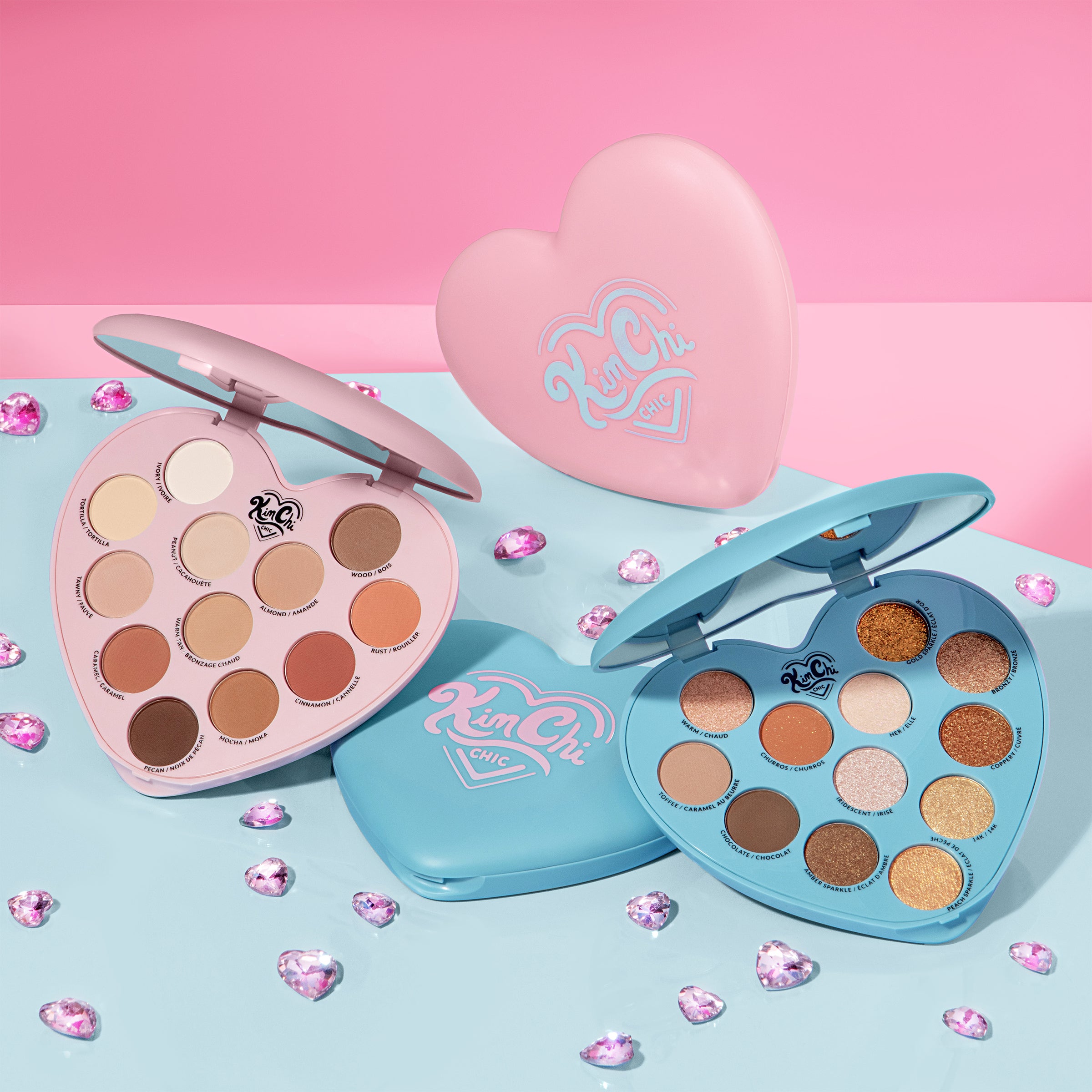 Two heart-shaped cosmetic palettes with a variety of eyeshadow colors on a colorful background.