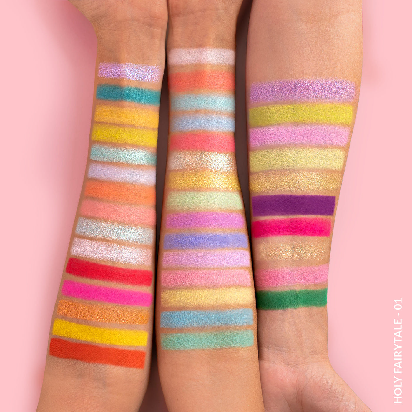 Three arms showing colorful eyeshadow swatches against a pink background.