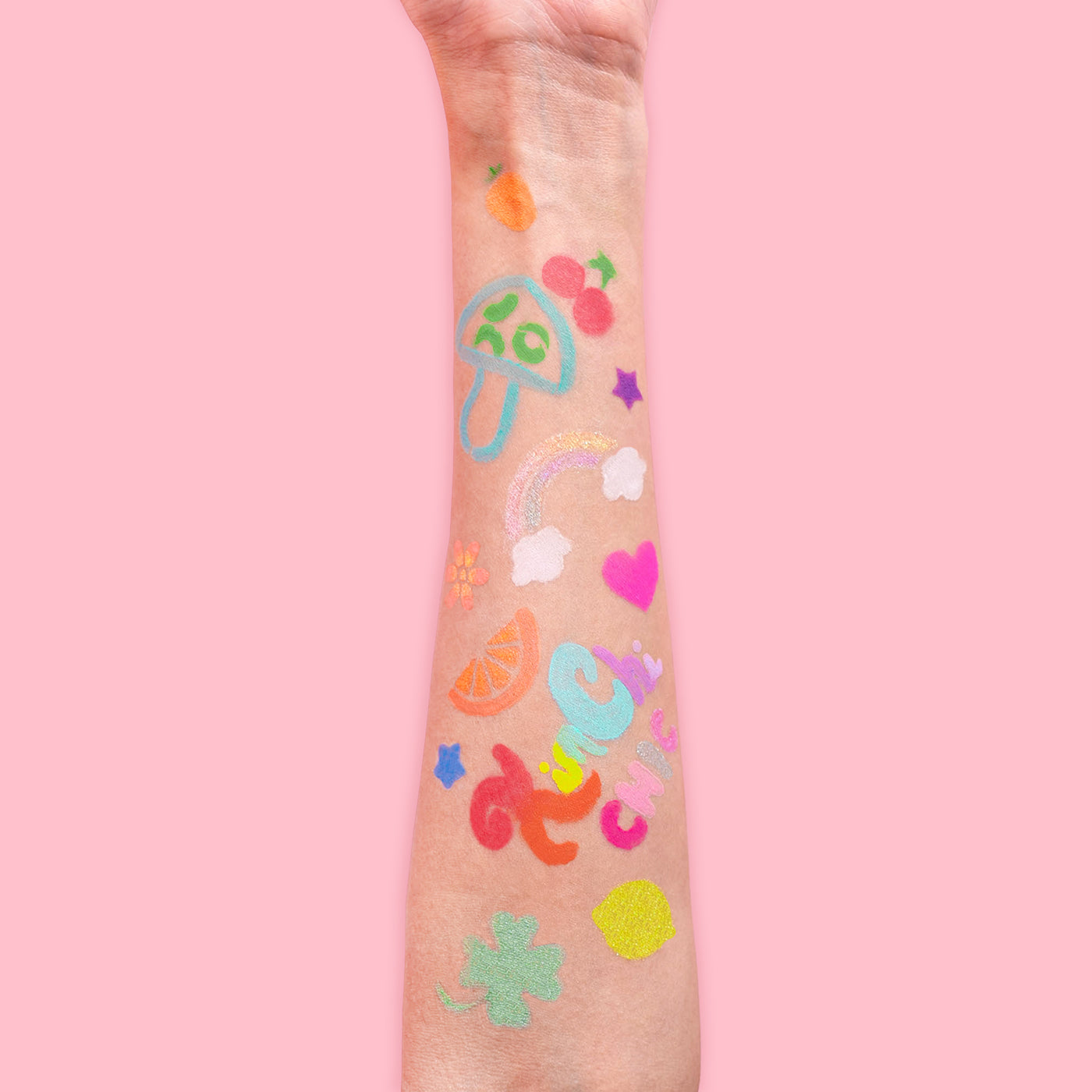 Arm with colorful temporary tattoos against a pink background