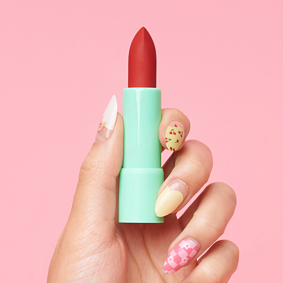 Hand holding red lipstick with decorated nails