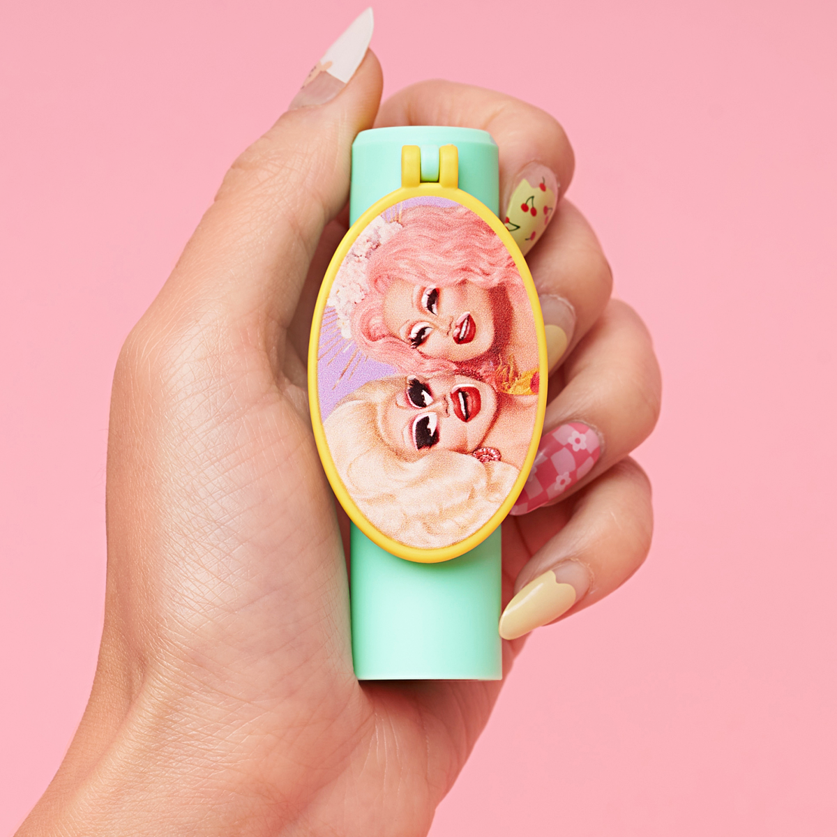Hand holding a pastel-colored lighter with a decorative panel featuring two faces on it.