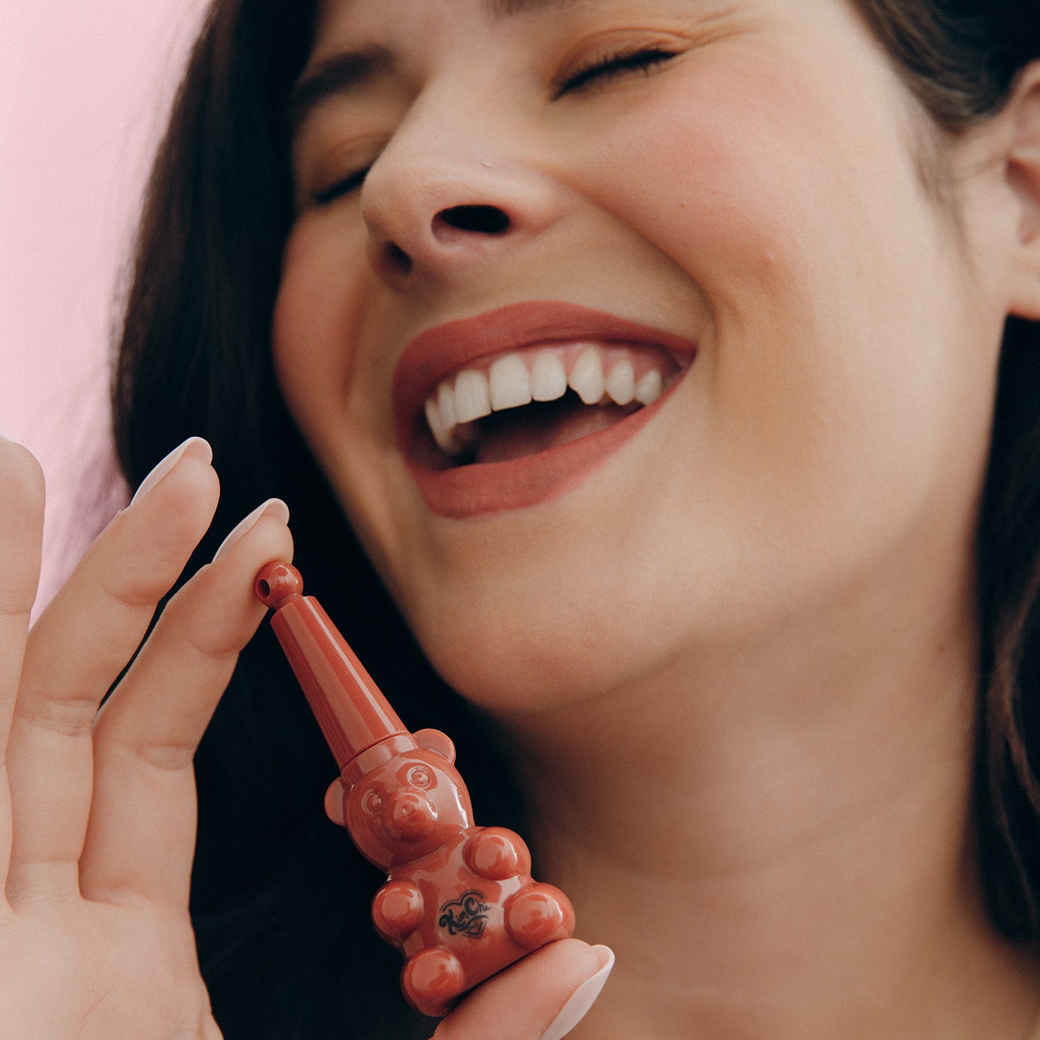 Woman smiling while holding a bear-shaped lip gloss tube