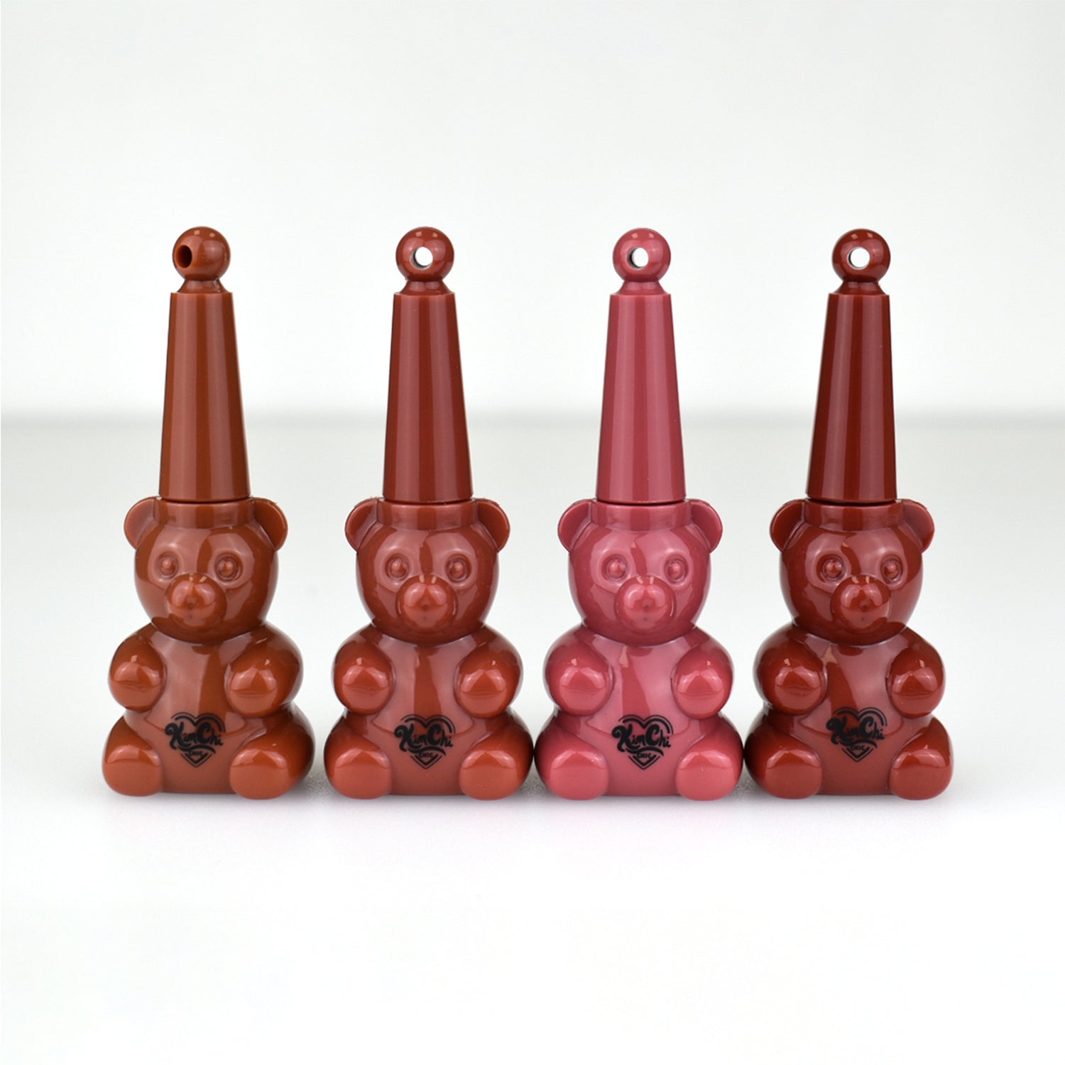 Four bear-shaped bottles with cone-shaped caps in varying shades of brown and pink.