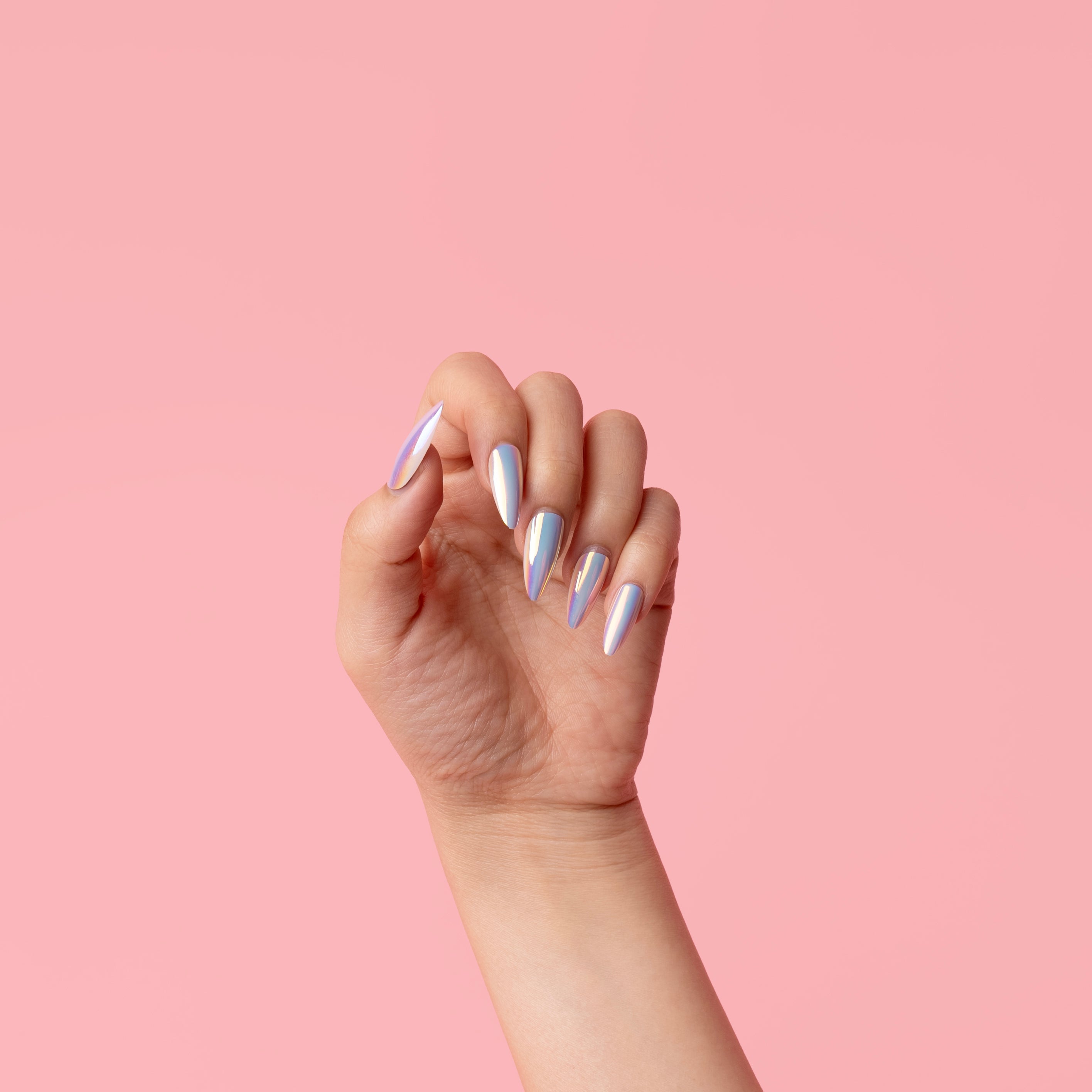 Hand with iridescent nail polish against a pink background