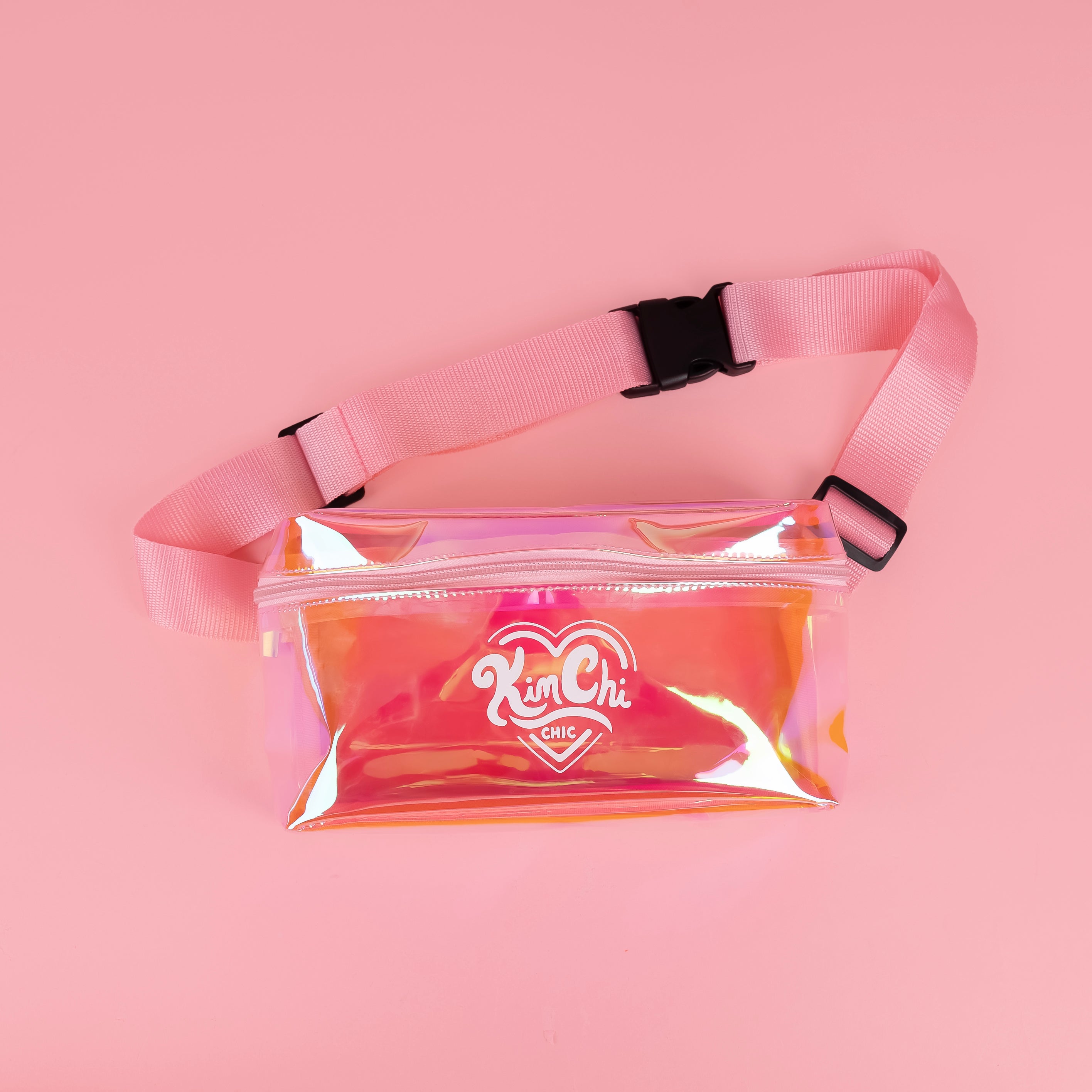 Iridescent fanny pack with pink strap on pink background