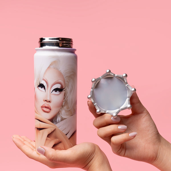 Person holding a decorated thermos and cap against a pink background.