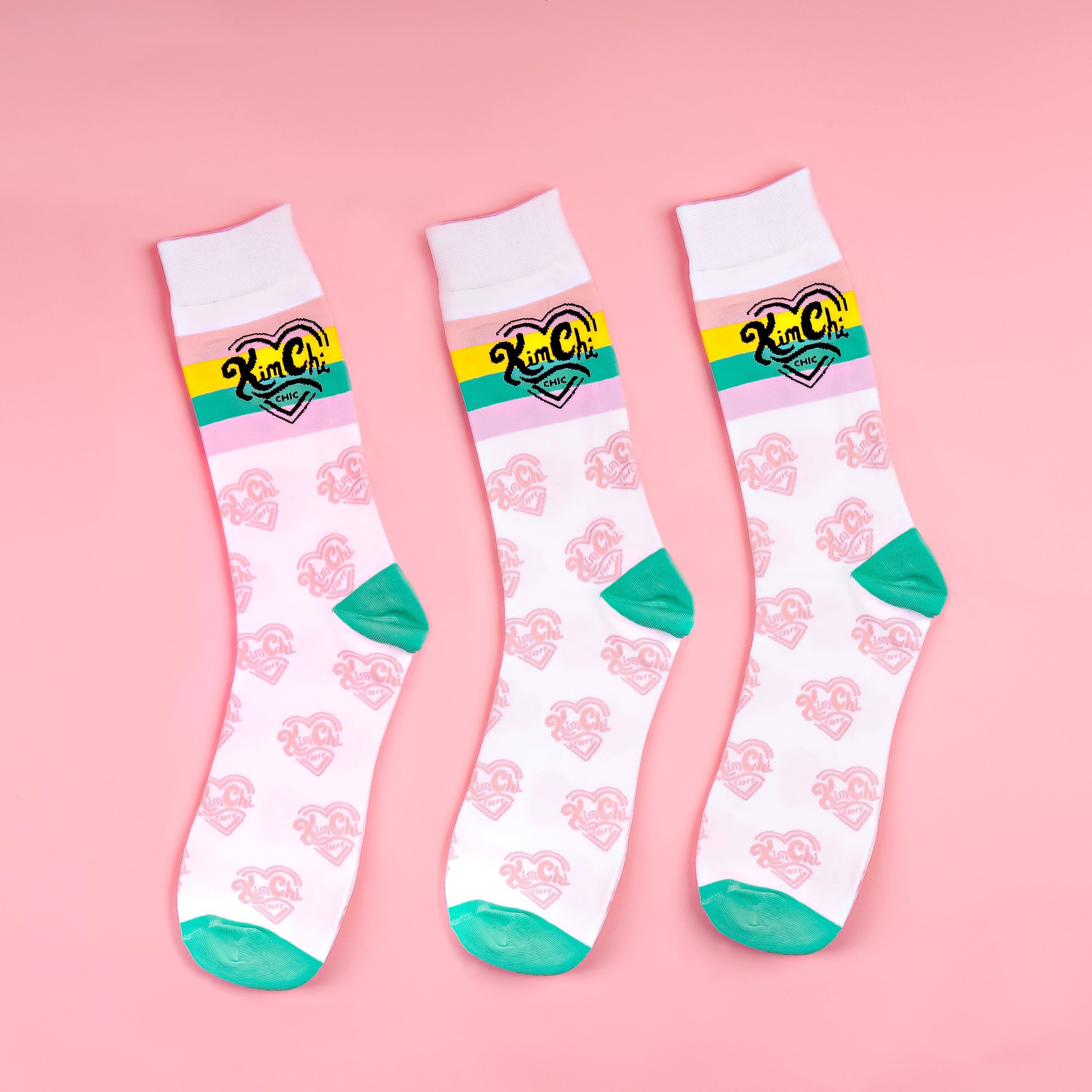 Three colorful socks with green toes and a retro pattern on a pink background.