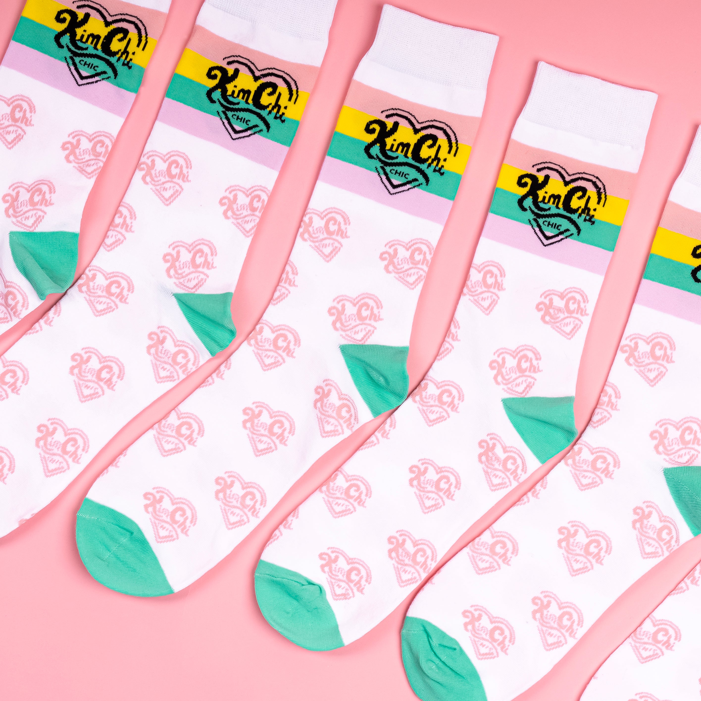 Colorful socks with graphics and logo on a pink background.