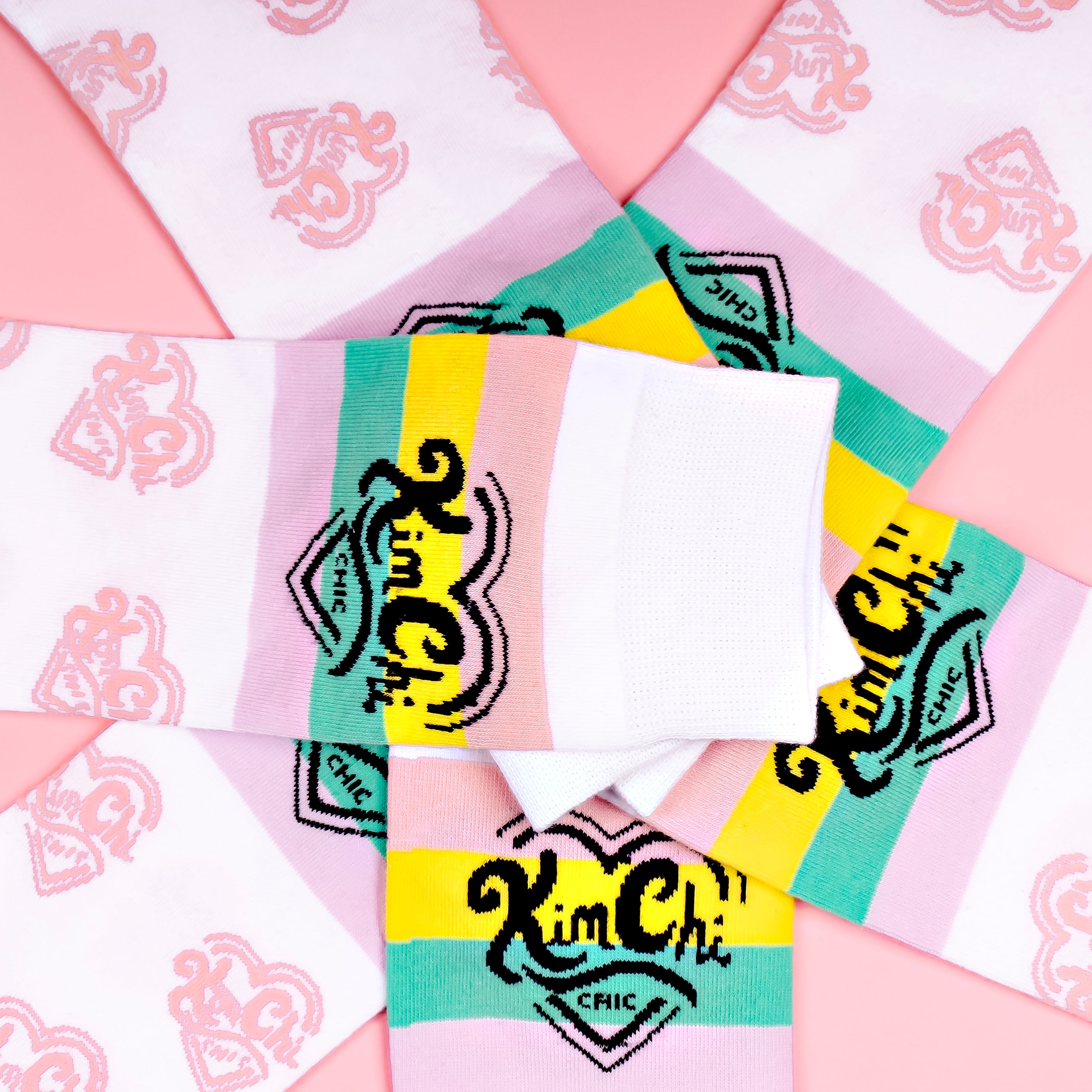 Colorful patterned socks arranged in a spiral on a pink background.