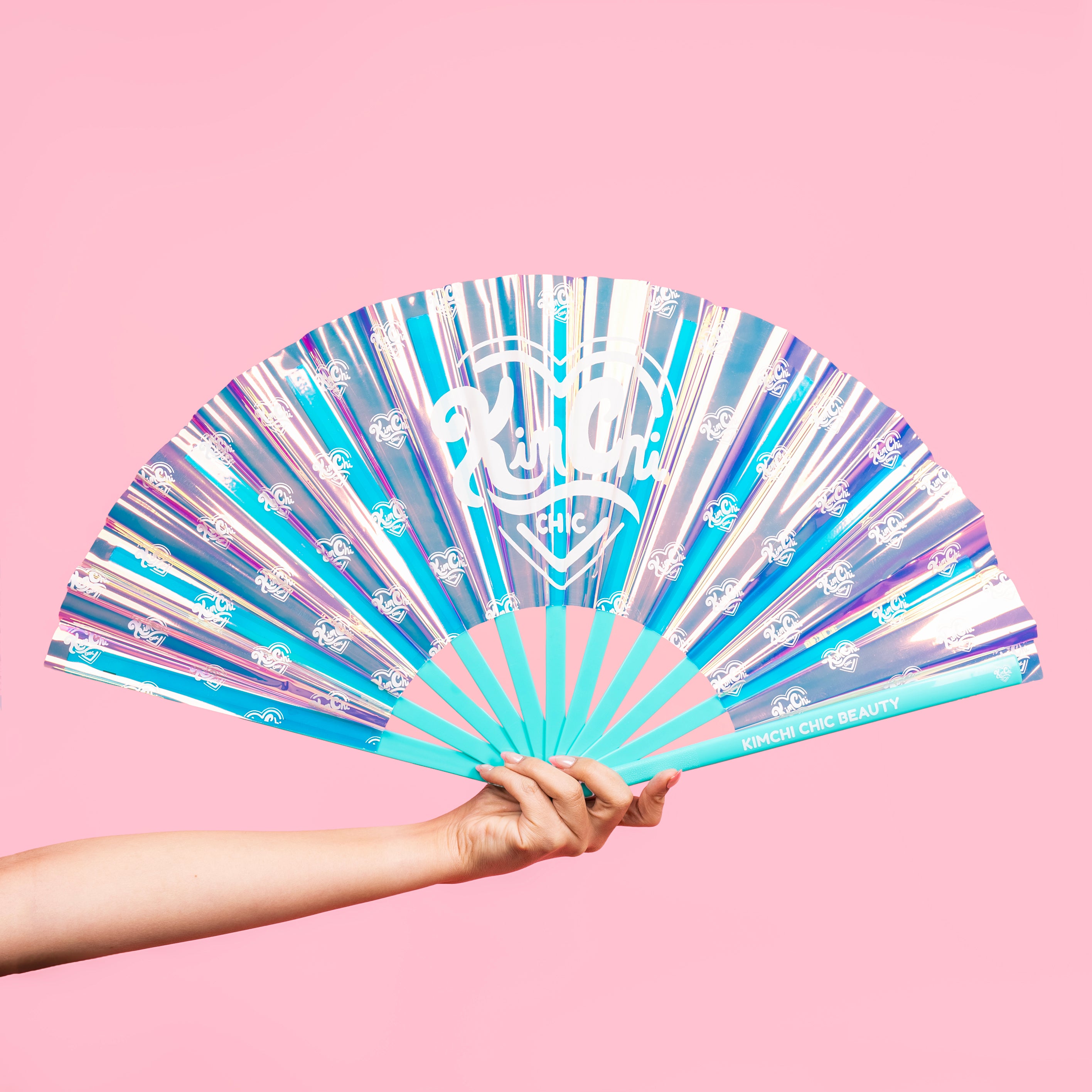 Person holding a colorful folding fan with a pink background