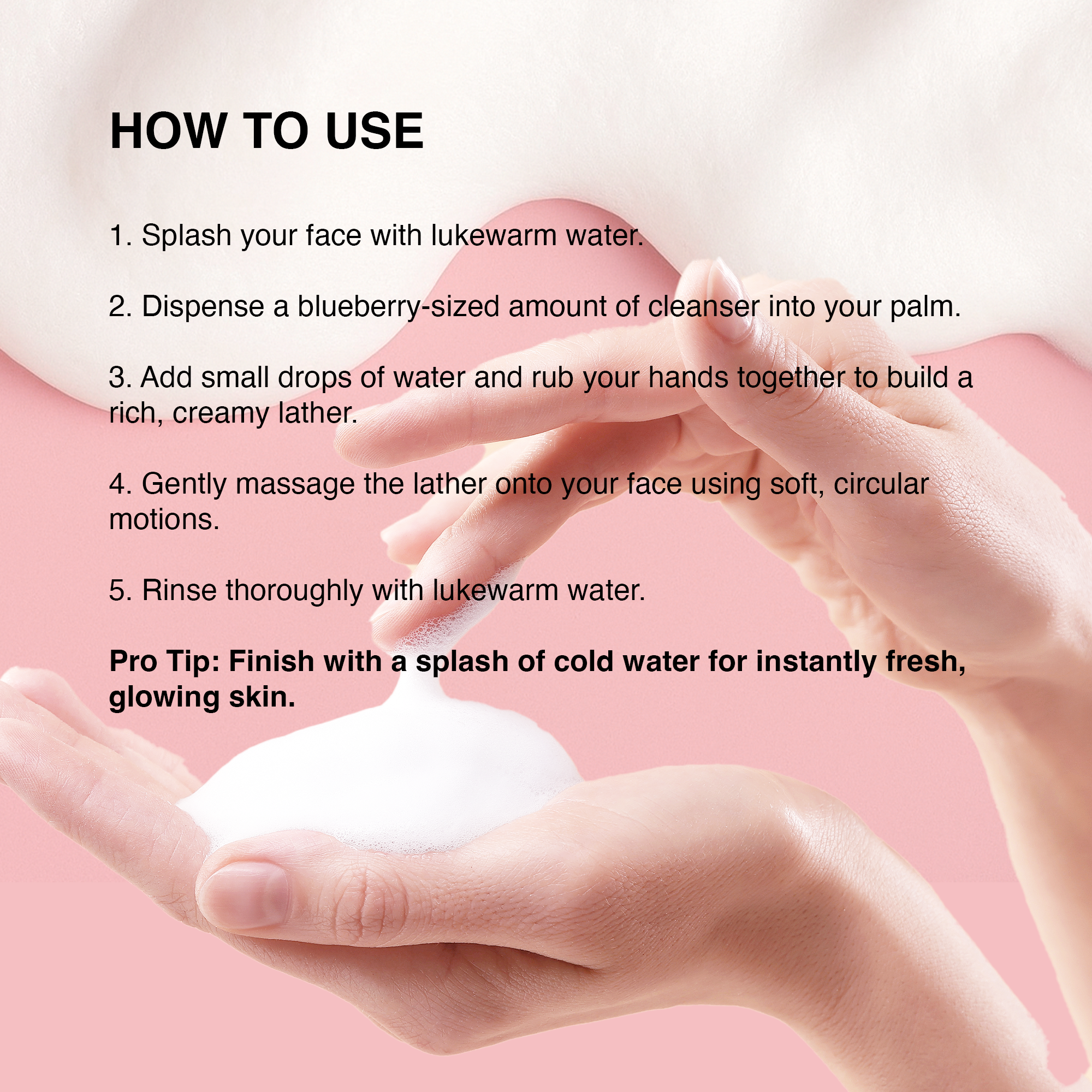 Hands applying creamy facial cleanser for a fresh, glowing complexion on a soft pink background.