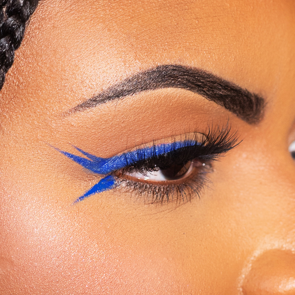 Close-up of a woman's eye with bold blue eyeliner and long eyelashes.