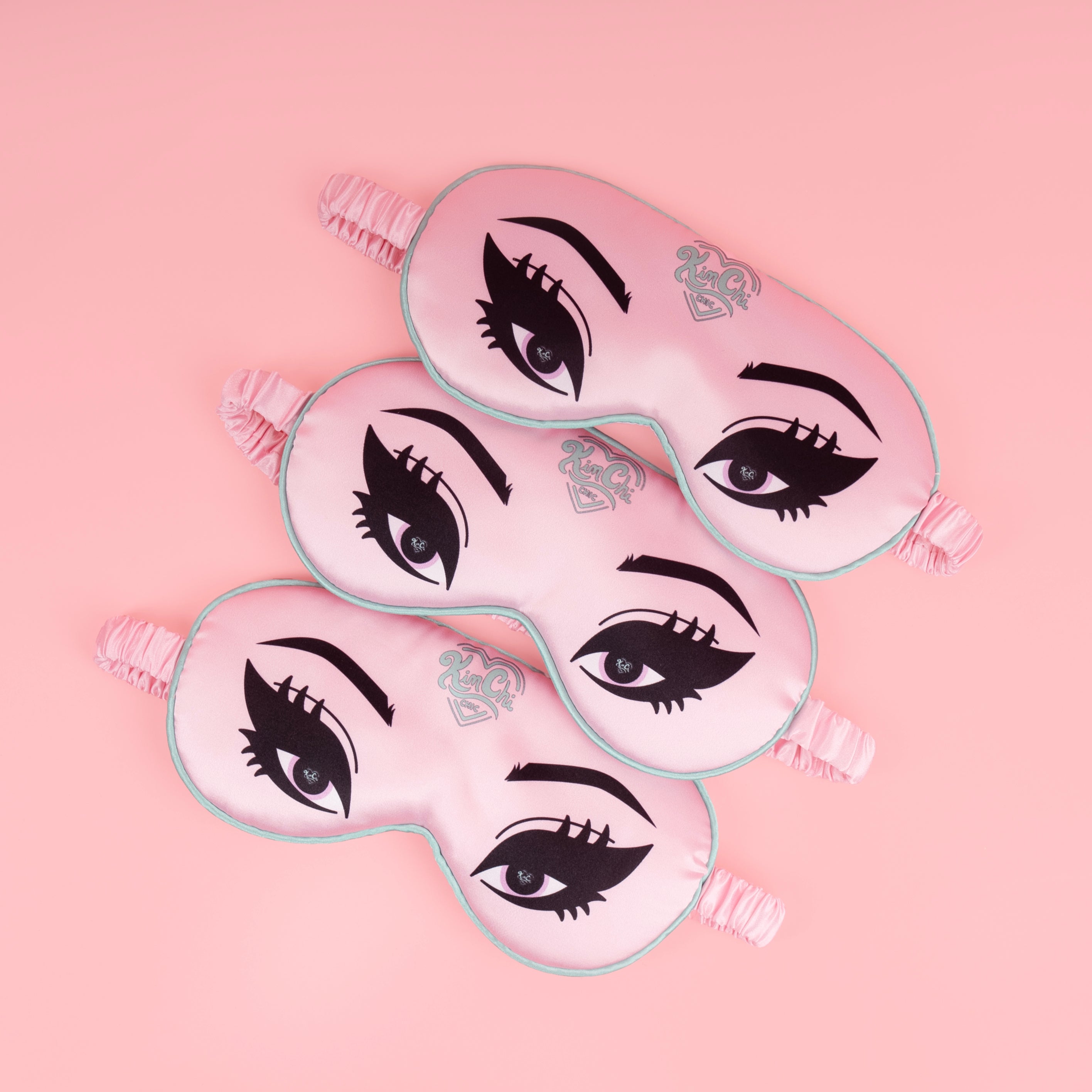 Pink sleep masks with eye designs on a pink background