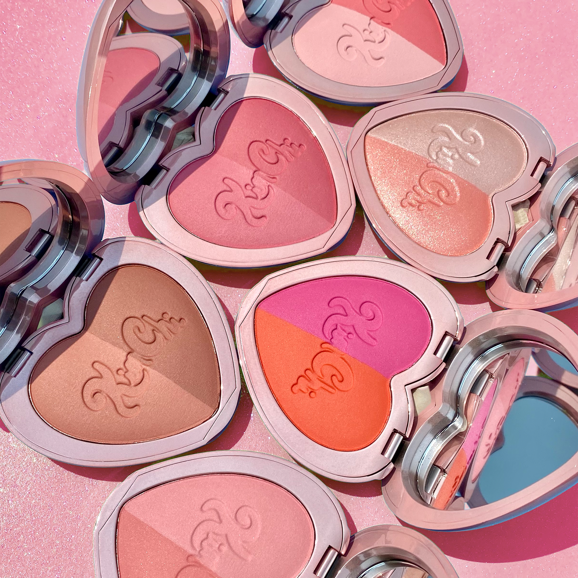 Colorful heart-shaped blush compacts in pink tones, featuring a mix of matte and shimmer finishes.