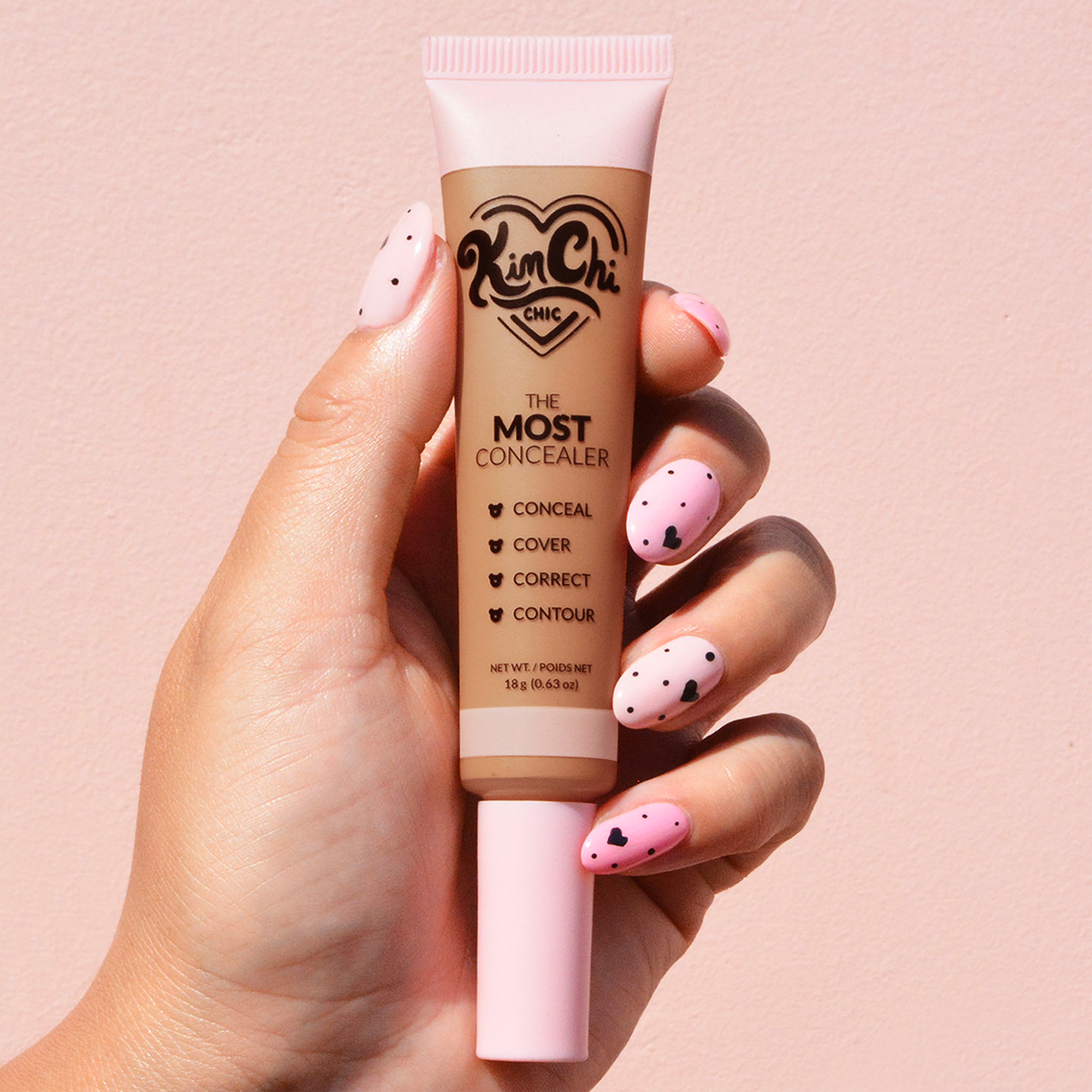 Hand holding Kim Chi concealer tube with pink polka dot nails