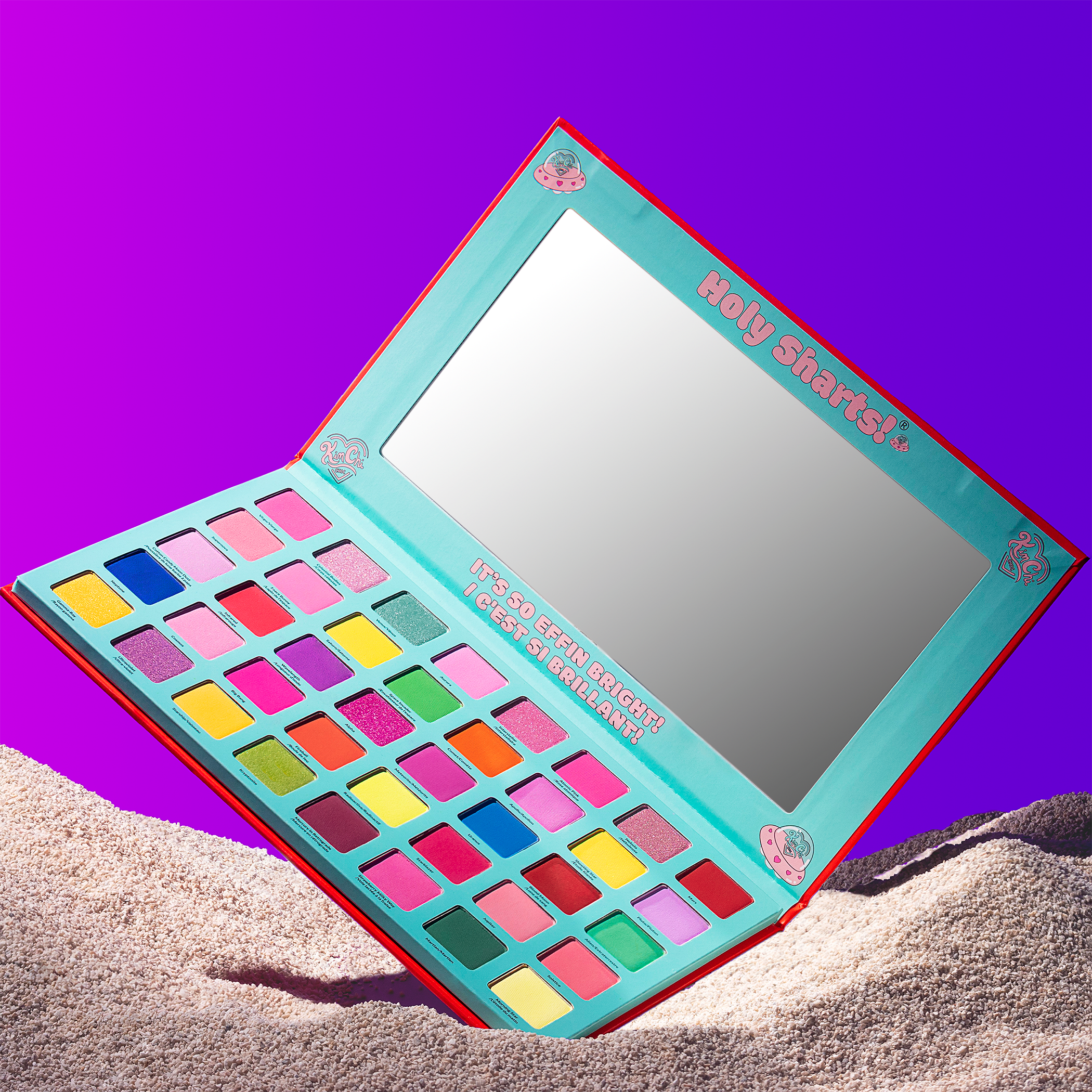 Colorful eyeshadow palette with mirror on sand