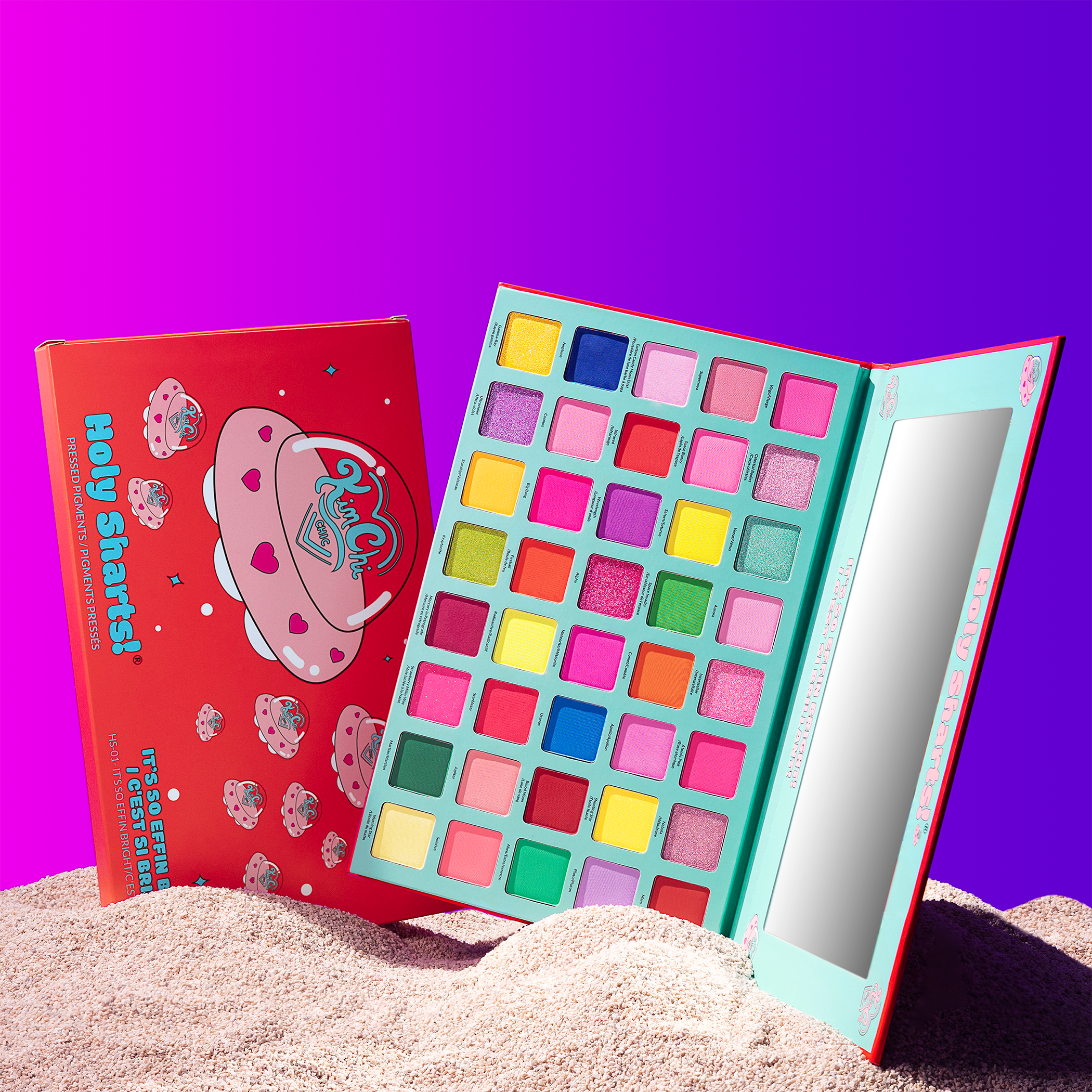 Colorful eyeshadow palette with a mirror on a sandy surface, vibrant background.