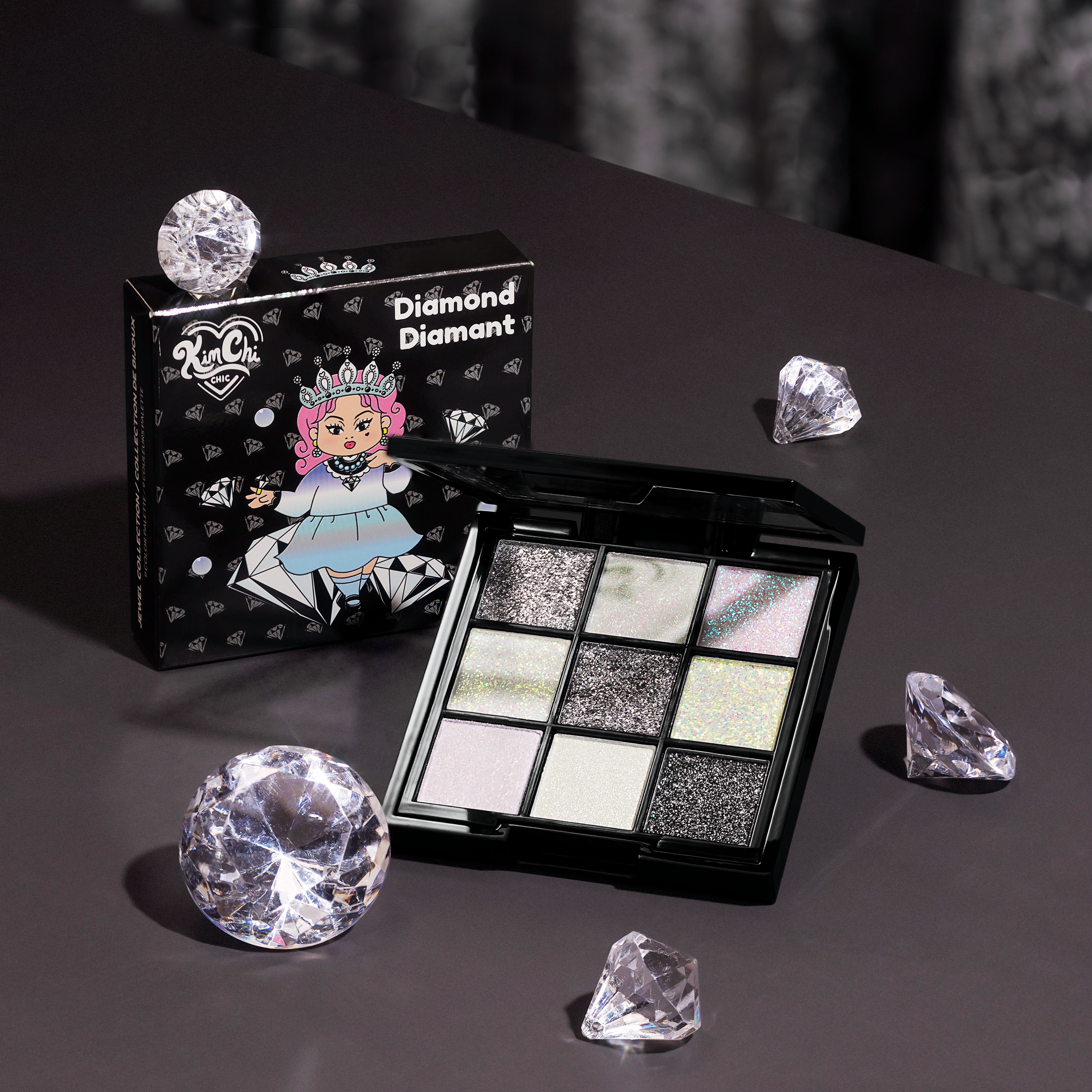 Makeup palette with shimmery shades surrounded by decorative gems and packaging.