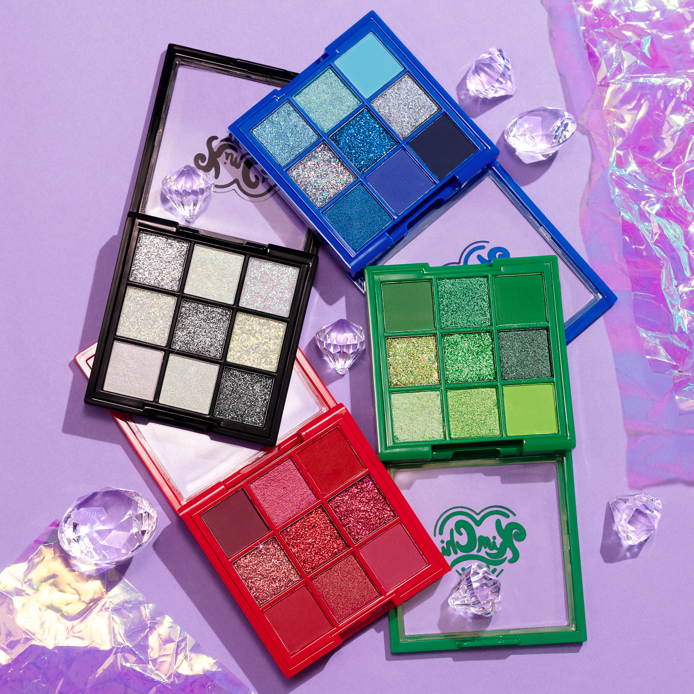 Colorful eyeshadow palettes and decorative crystals on a purple background