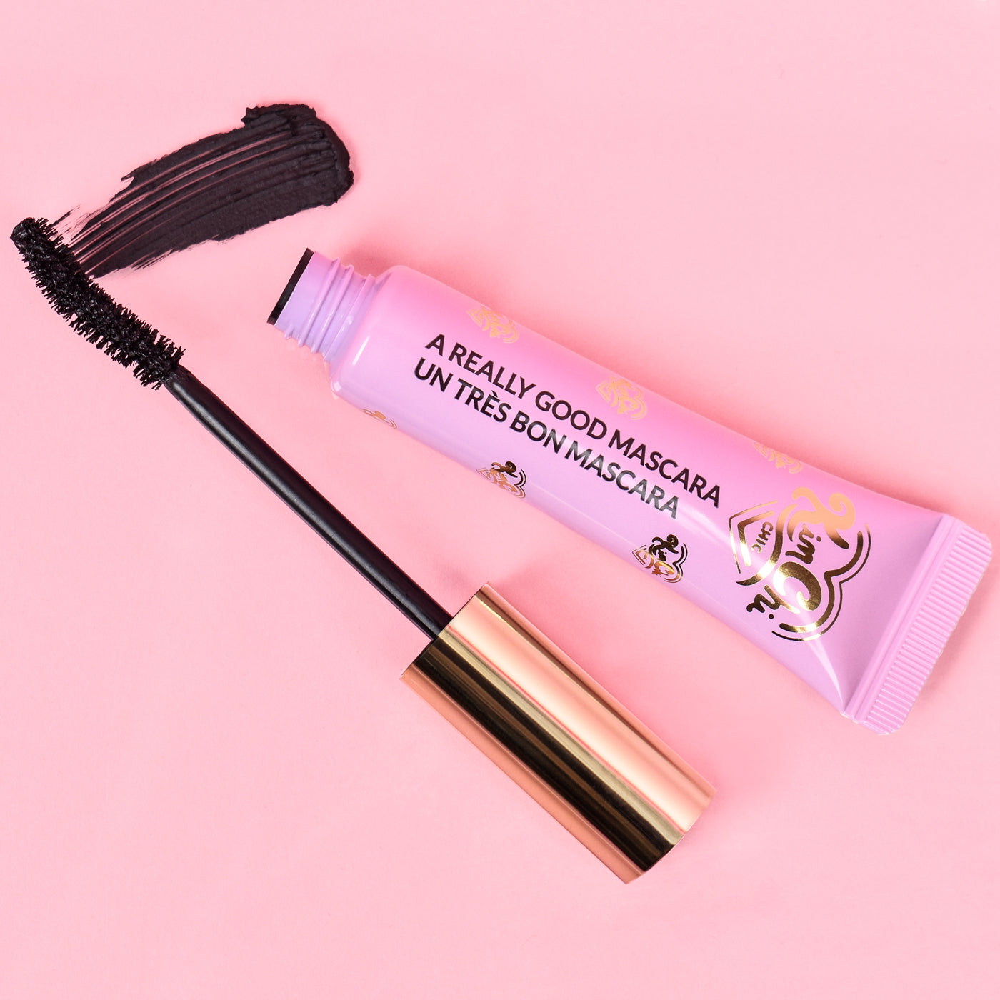 Mascara tube with applicator on pink background