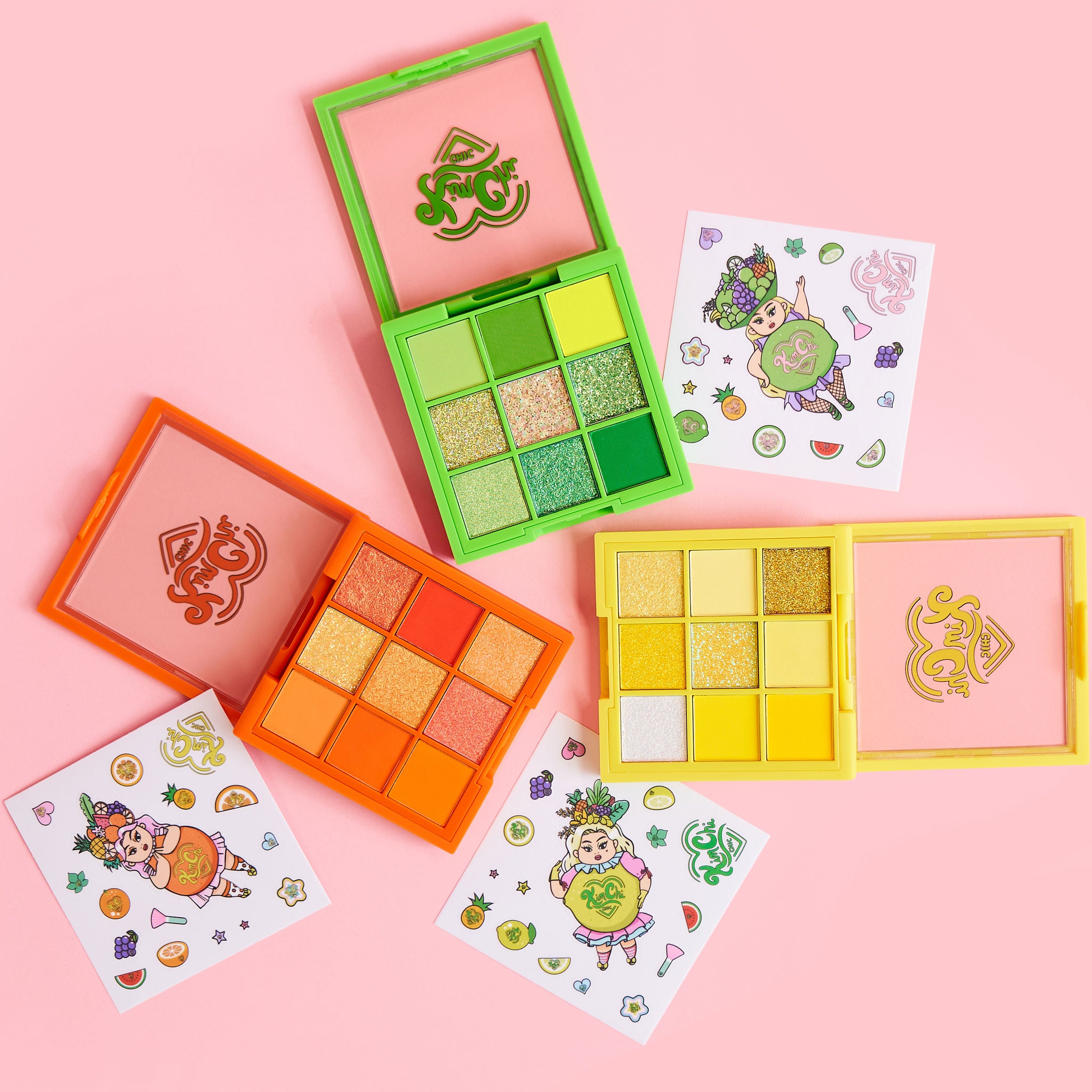 Colorful eyeshadow palettes with stickers on a pink background