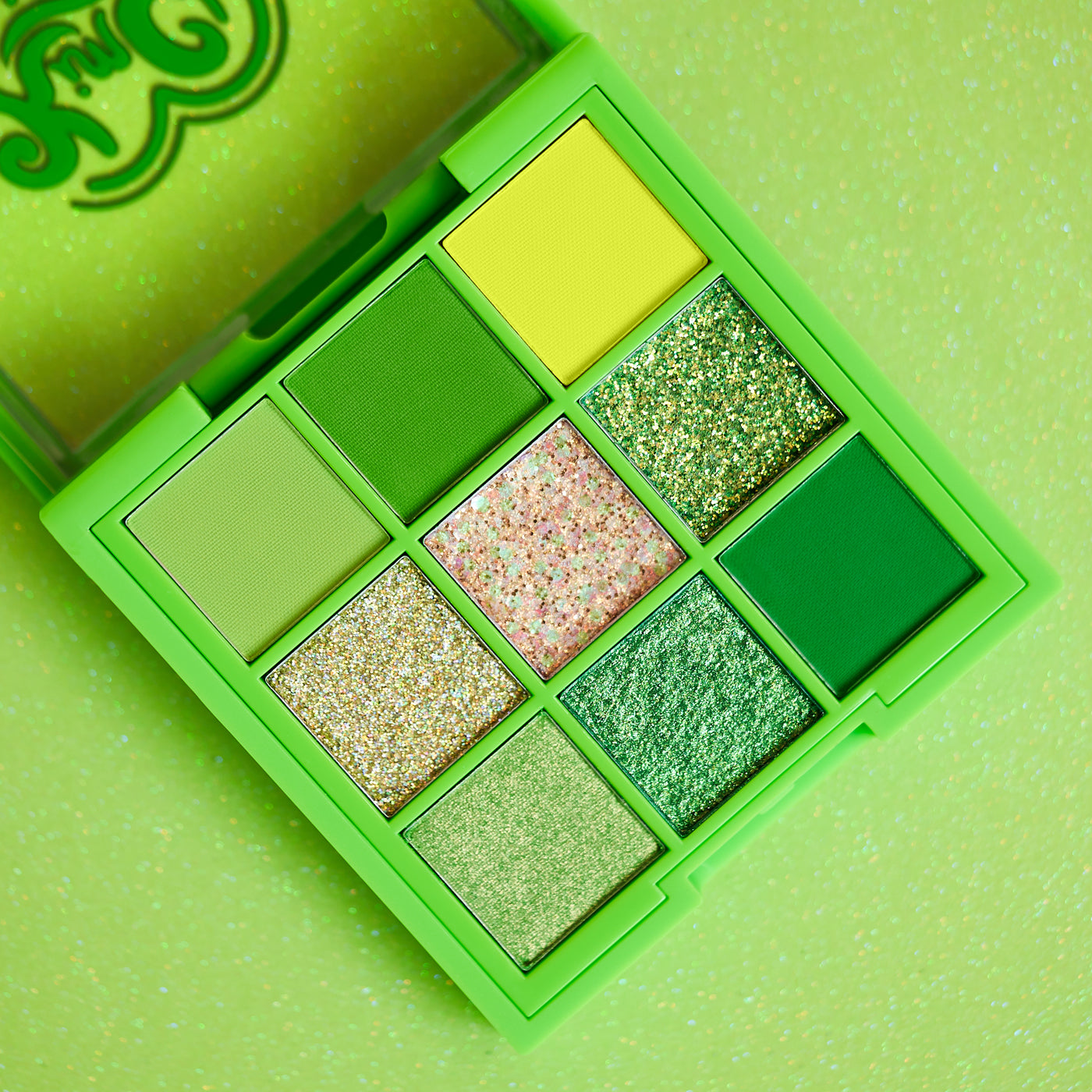 Green eyeshadow palette with various shades and glitter.