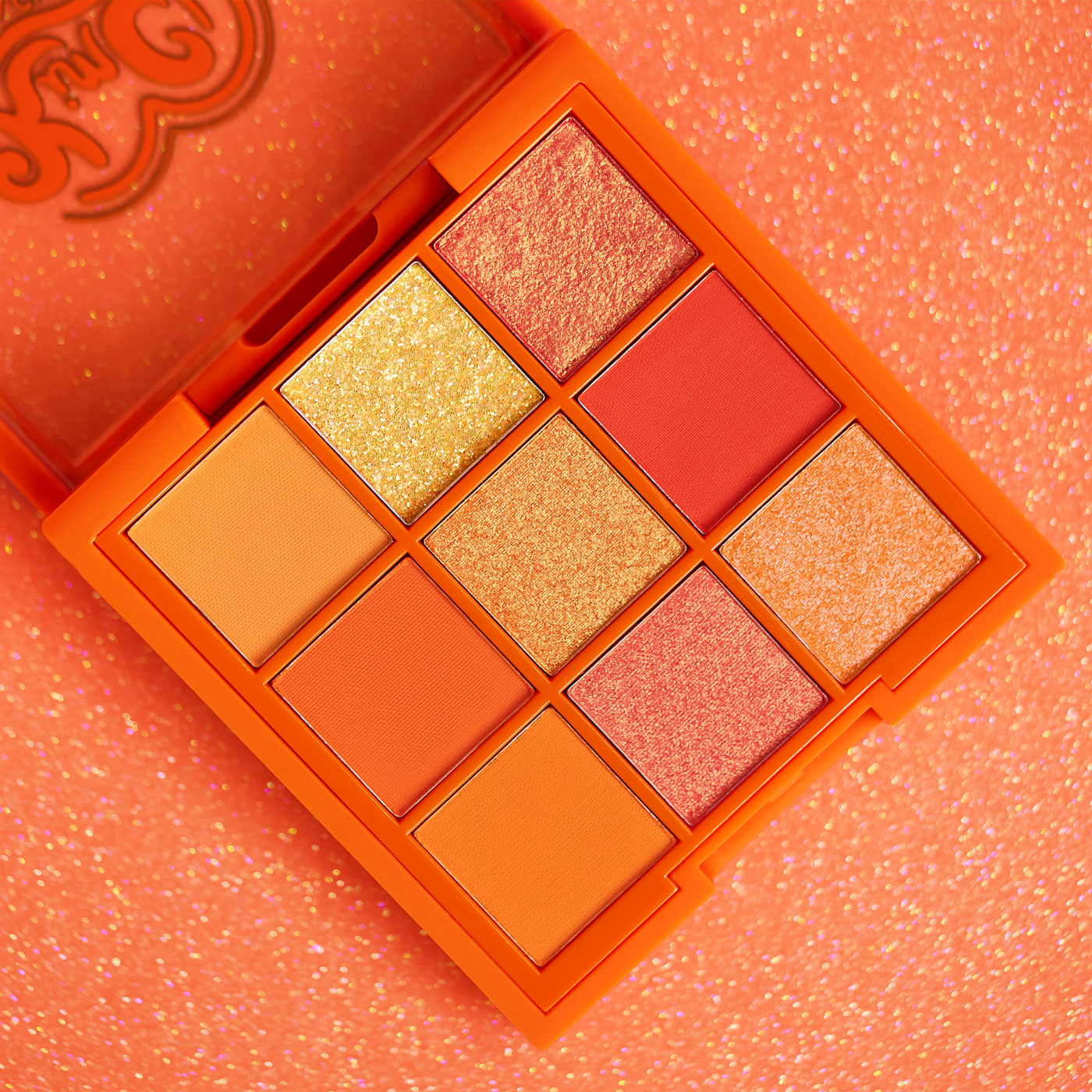 Nine-color orange and gold eyeshadow palette on sparkly background