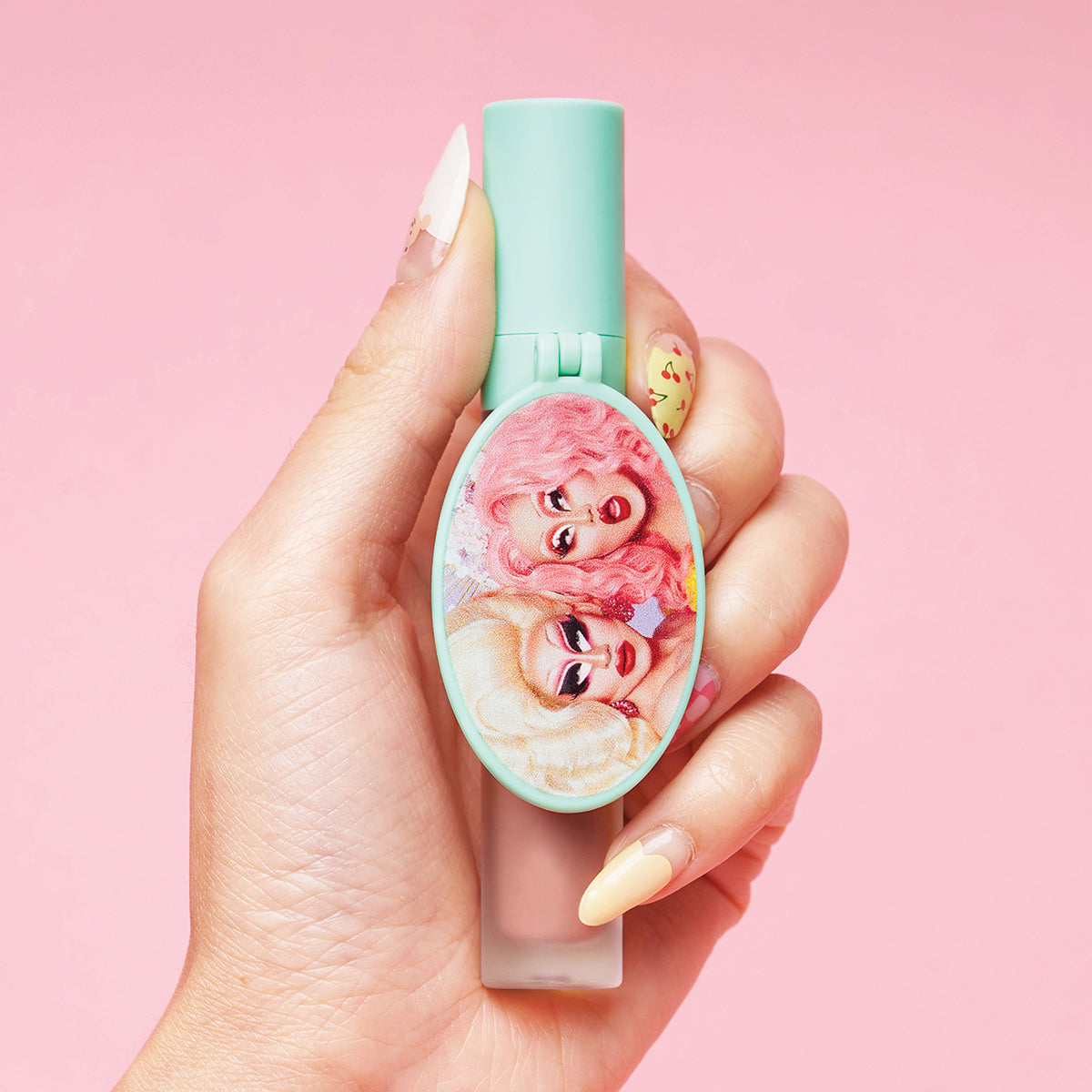 Person holding a pastel-colored makeup product with illustrated faces.